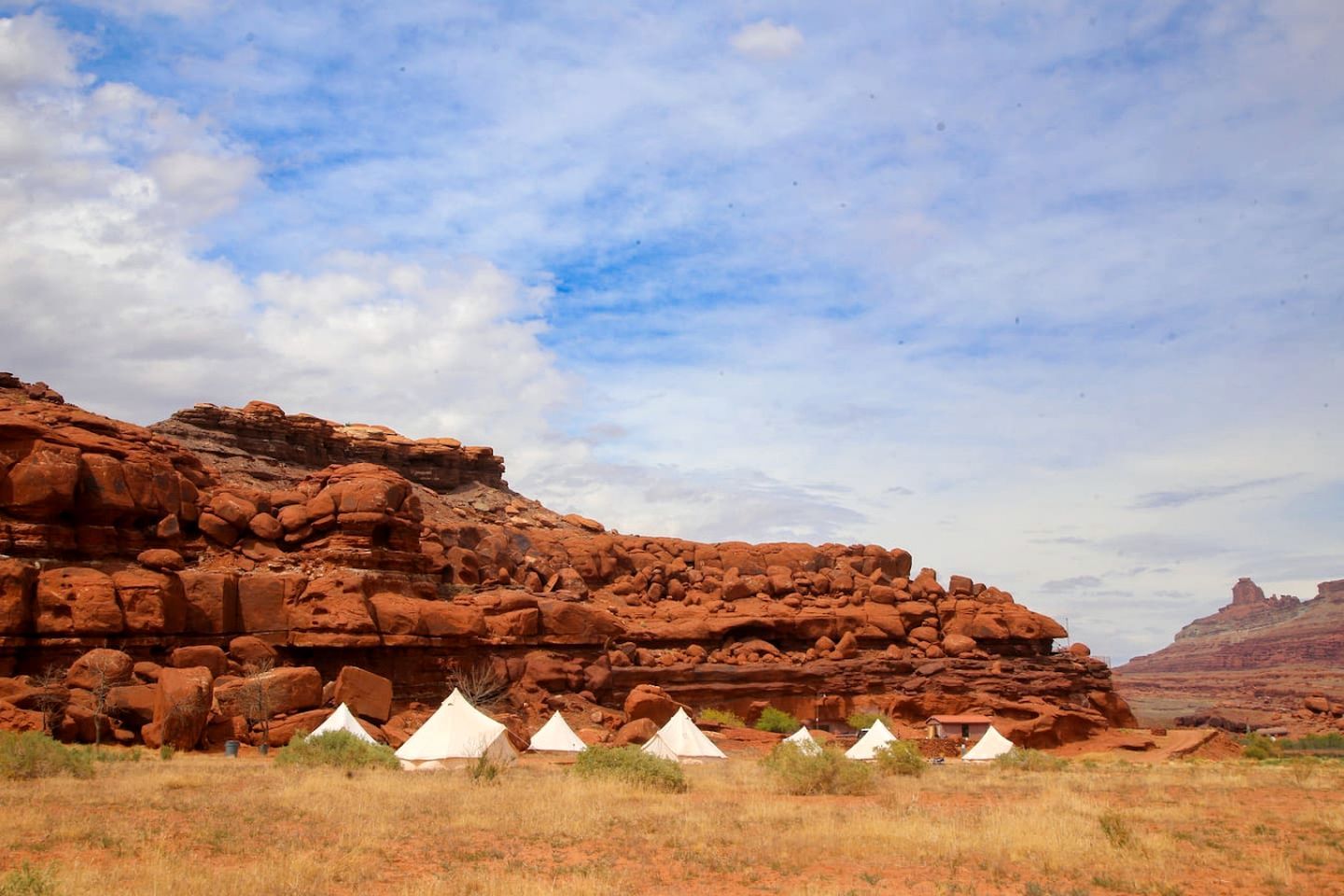 A desert landscape with red rock formations and white tents.