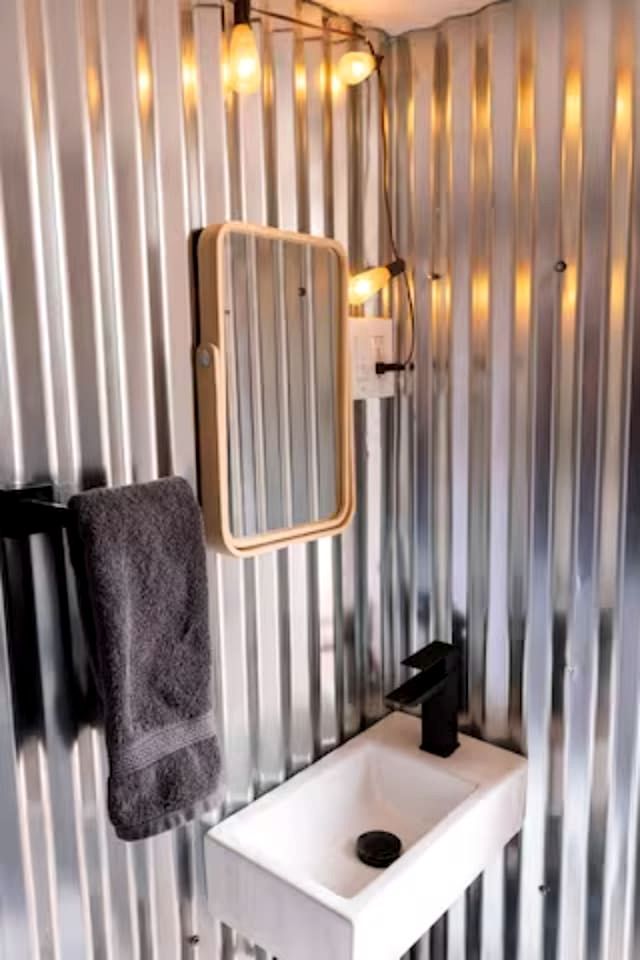Un baño con un lavamanos blanco, un perchero y un espejo.