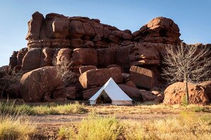 Une tente devant une grande formation rocheuse.