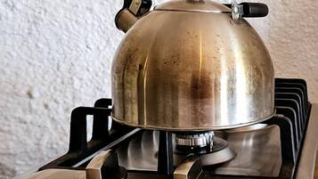 A gas stove with a pot on top, a control knob, and a burner.