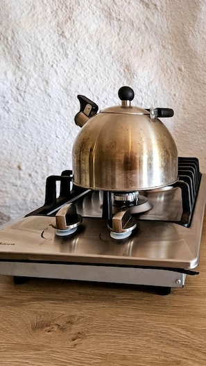 Ein Gaskochfeld mit einem Topf, einem Regler und einem Brenner.