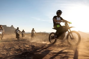 Eine Gruppe Motorradfahrer auf einer staubigen Straße unter blauem Himmel.