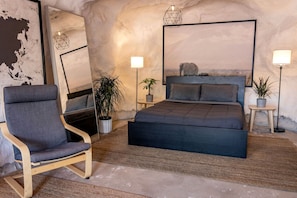 A bedroom with a bed, a chair, and two bedside tables with lamps.