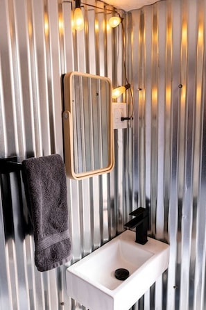 Une salle de bain avec un lavabo blanc, une serviette accrochée au mur et un miroir.