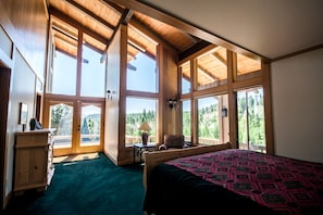 Ein geräumiges Schlafzimmer mit großen Fenstern, einem Bett, einem Schreibtisch und einem Stuhl.