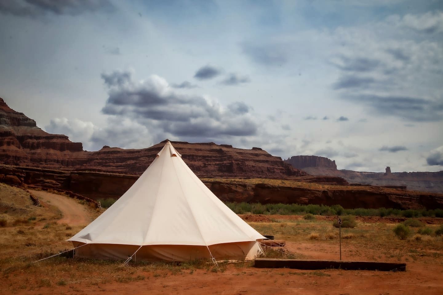 A white tent in a desert landscape with red rock formations in the background.