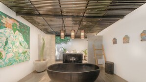 Une salle de bain moderne avec une grande baignoire sur pieds, un lavabo en béton et une échelle en bois.