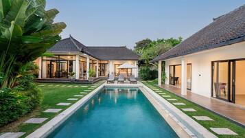 A modern house with a swimming pool, two separate buildings, and a well-maintained garden.