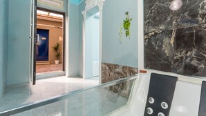 Una hall moderna con ringhiera in vetro, parete in marmo e una porta che dà su un'altra stanza.