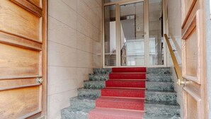 A staircase with red carpet, wooden doors, and marble steps.