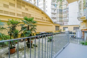 A courtyard with potted plants, a metal railing, and a building with balconies. - GuestHost - Elegant Apartment Crocetta Torino (Turin)
