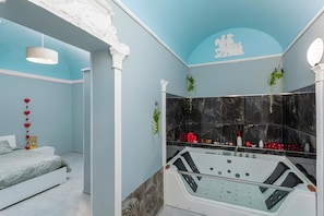 Un baño moderno con bañera, paredes de mármol y plantas decorativas.