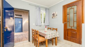 Un comedor con una mesa, sillas, una puerta azul y una puerta de madera.