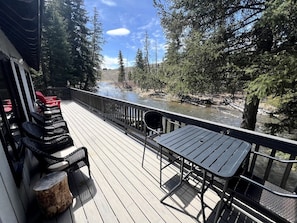 A wooden deck with outdoor seating, overlooking a river and forested area.