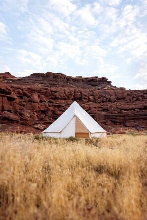A white tent in a grassy field with a rocky backdrop. - Beautiful Glamping Tent for an Unforgettable Family Escape near Canyonlands National Park in Moab, Utah (Moab)