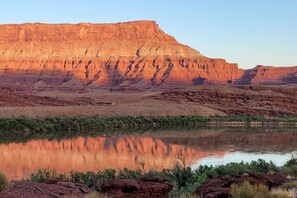 A natural landscape with a river reflecting a mountain range.