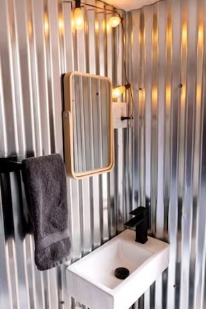 A bathroom with a white sink, a towel rack, and a mirror.