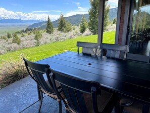 A patio with a table and chairs, overlooking a mountainous landscape.