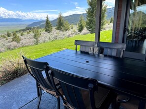 A patio with a table and chairs, overlooking a mountainous landscape.