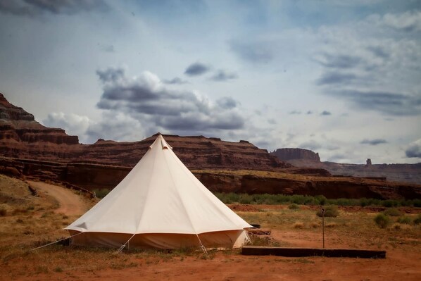 A white tent in a desert landscape with red rock formations in the background.