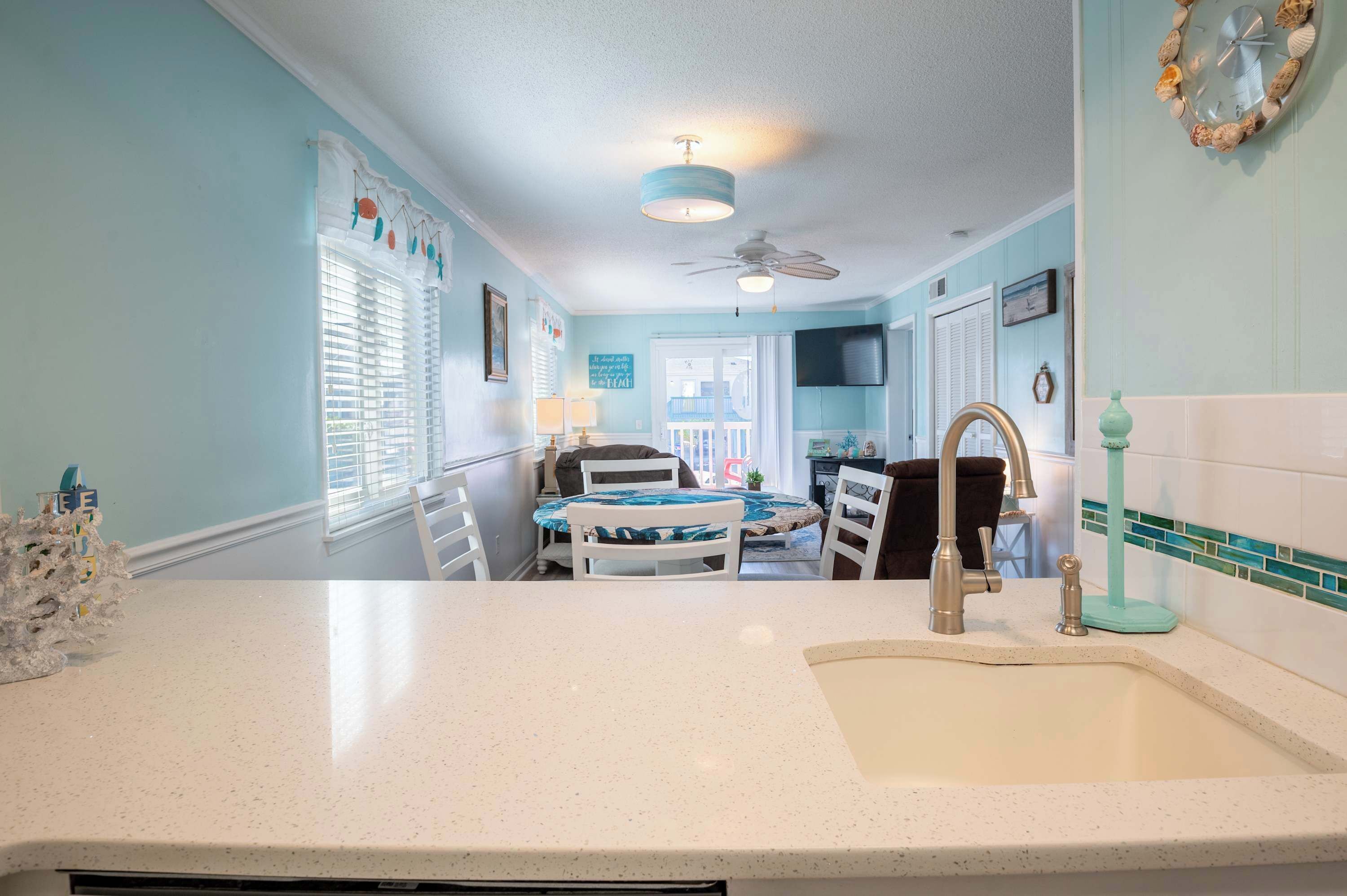 A kitchen with a sink, a dining area with a table and chairs, and a ceiling fan.