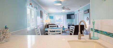 A kitchen with a sink, a dining area with a table and chairs, and a ceiling fan.