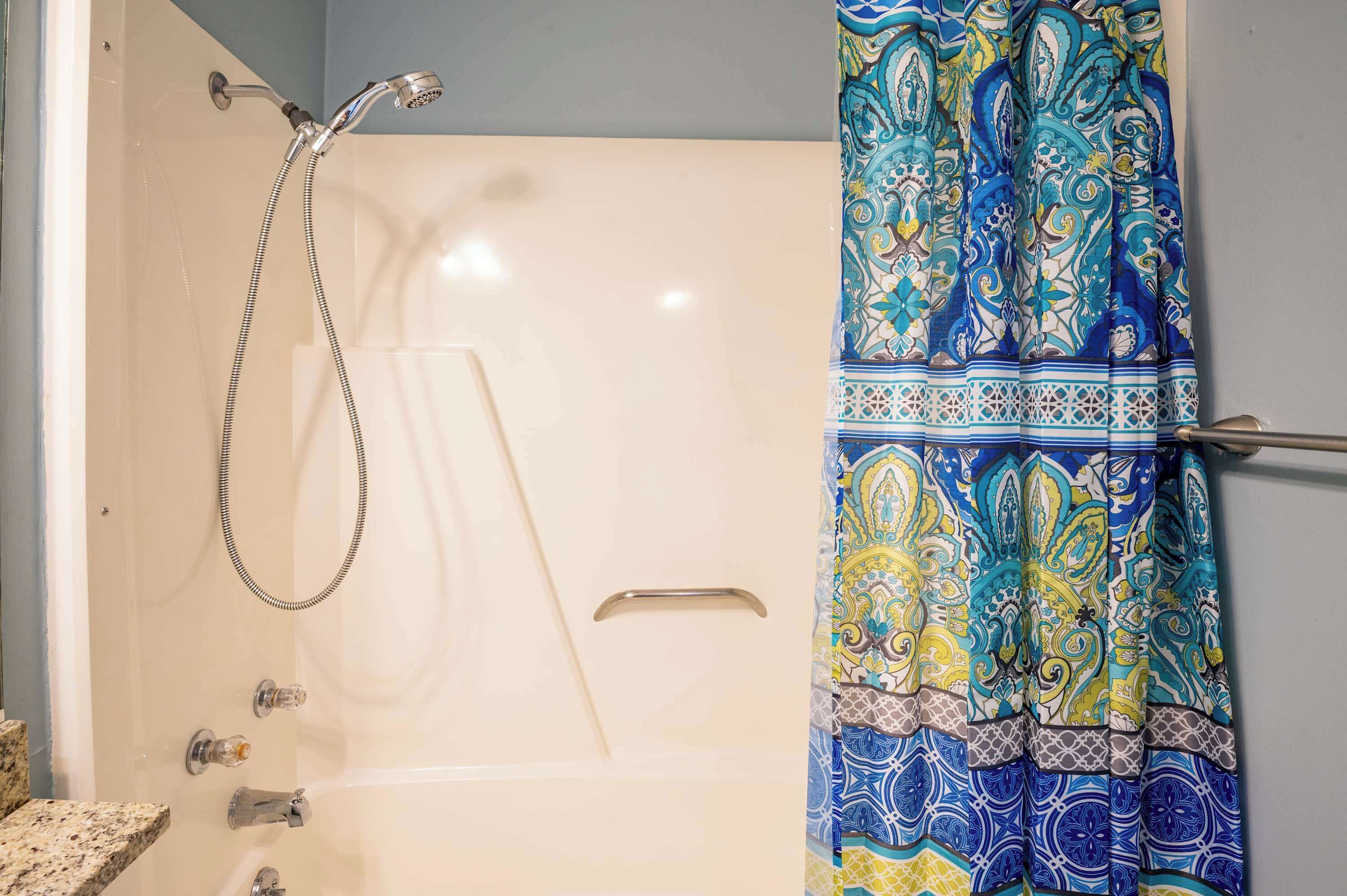 Un baño con ducha, perchero para toallas y cortina de ducha estampada.