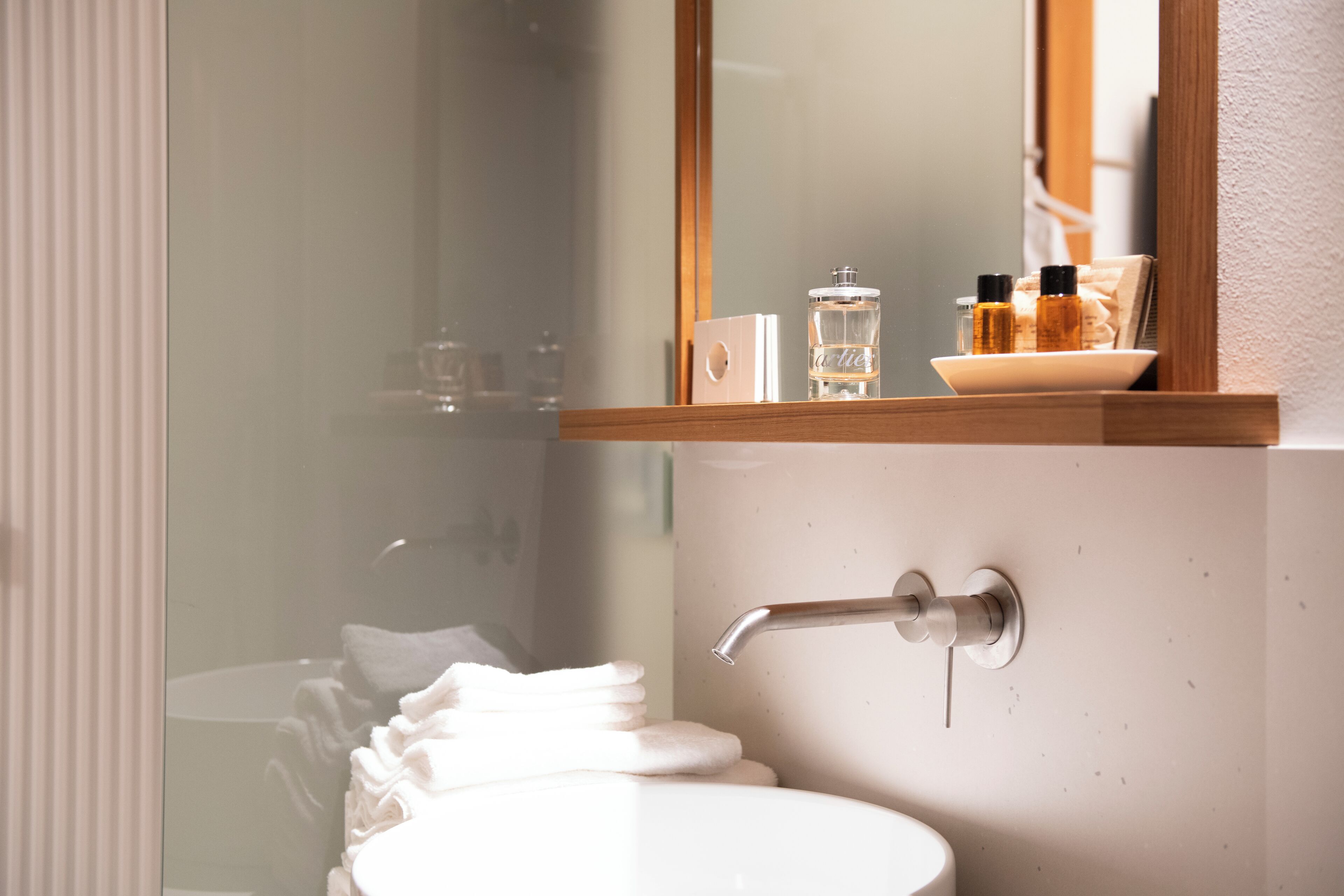 Une salle de bain avec un lavabo, un miroir et des articles de toilette rangés sur une étagère.