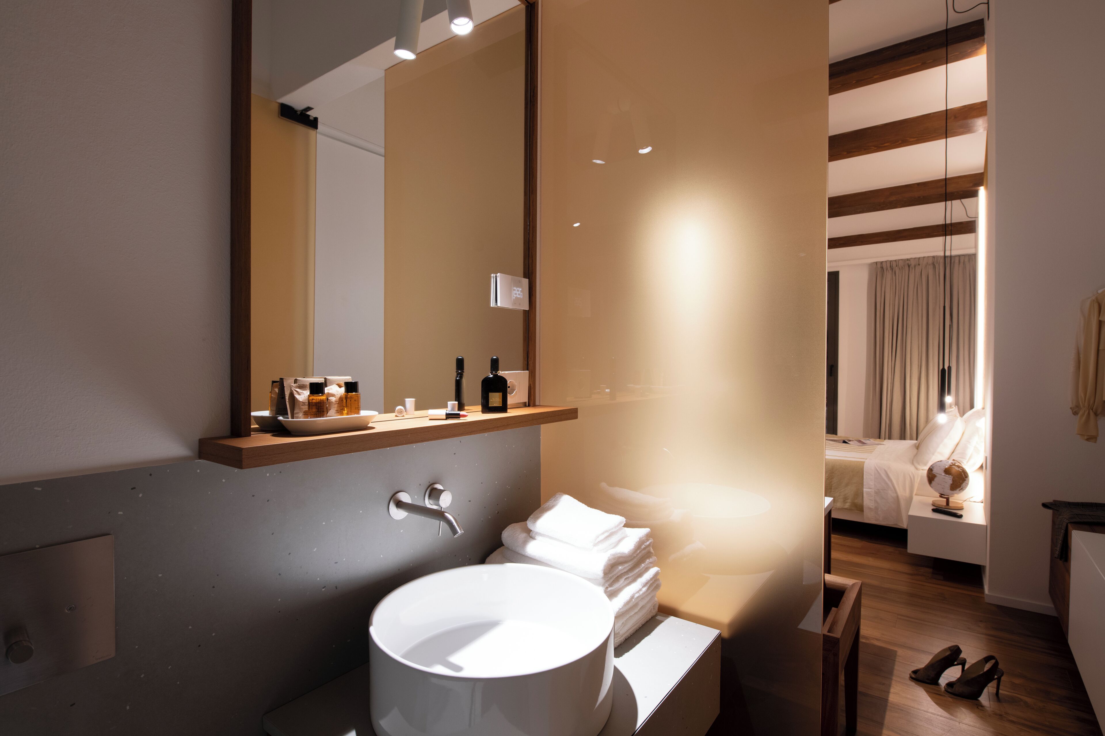 Ein modernes Badezimmer mit einem großen Waschbecken, einem Spiegel und einem Holzregal mit Toilettenartikeln.
