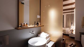 Ein modernes Badezimmer mit einem großen Waschbecken, einem Spiegel und einem Holzregal mit Toilettenartikeln.