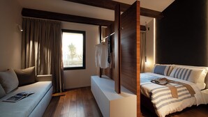 Ein modernes Schlafzimmer mit einer Couch, einem Bett mit gestreifter Bettwäsche, Holzbalken und einem Fenster mit Vorhängen.