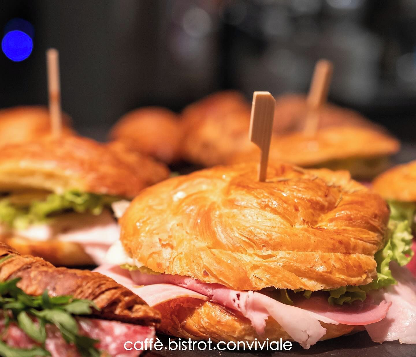 Primer plano de sándwiches con palillos, posiblemente en un café o evento.