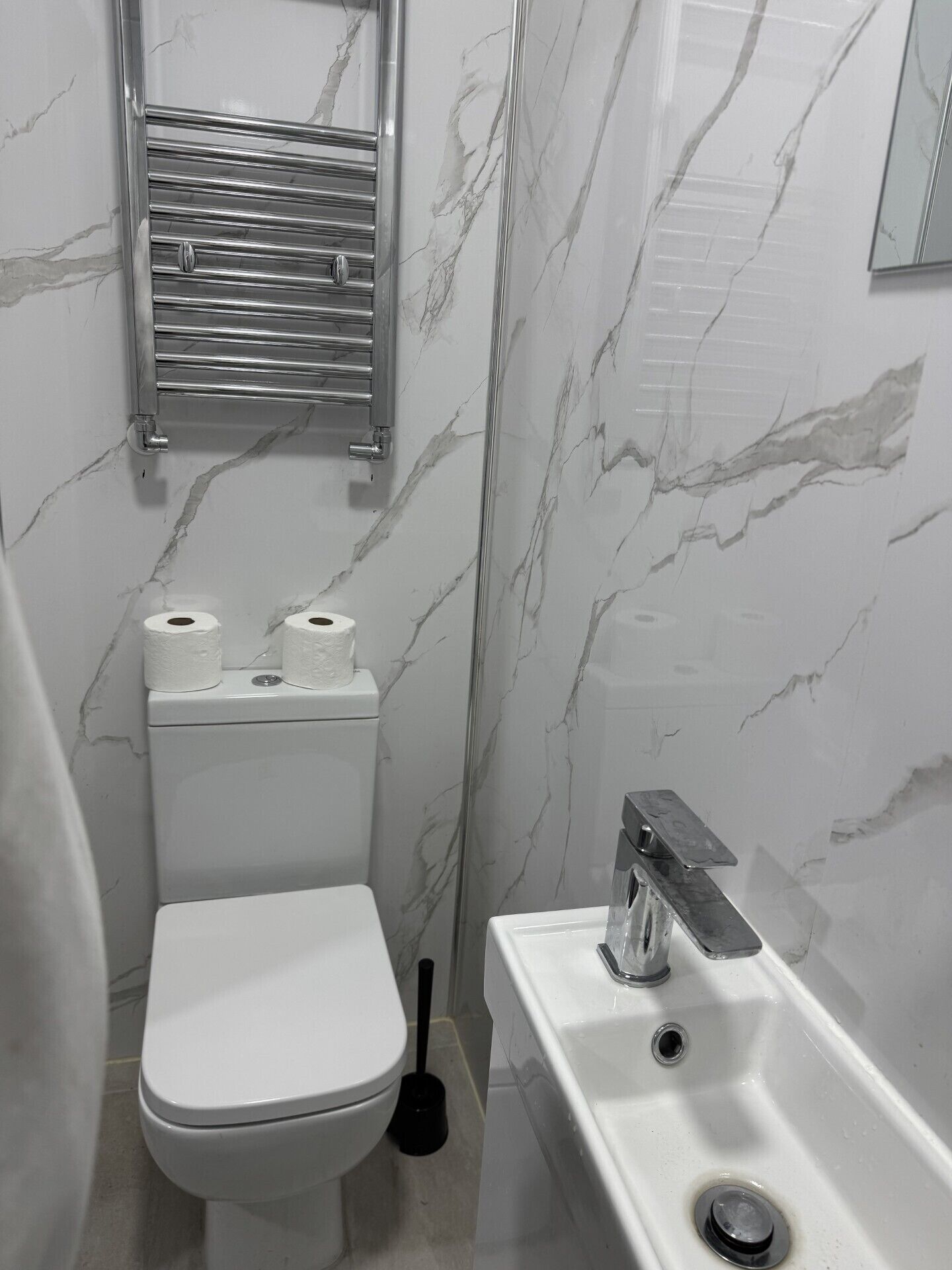 Egy fürdőszoba, amelyben WC, mosdókagyló és tükör található.