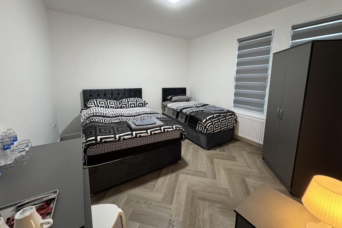 A bedroom with two beds, a wardrobe, a desk, and a chair.