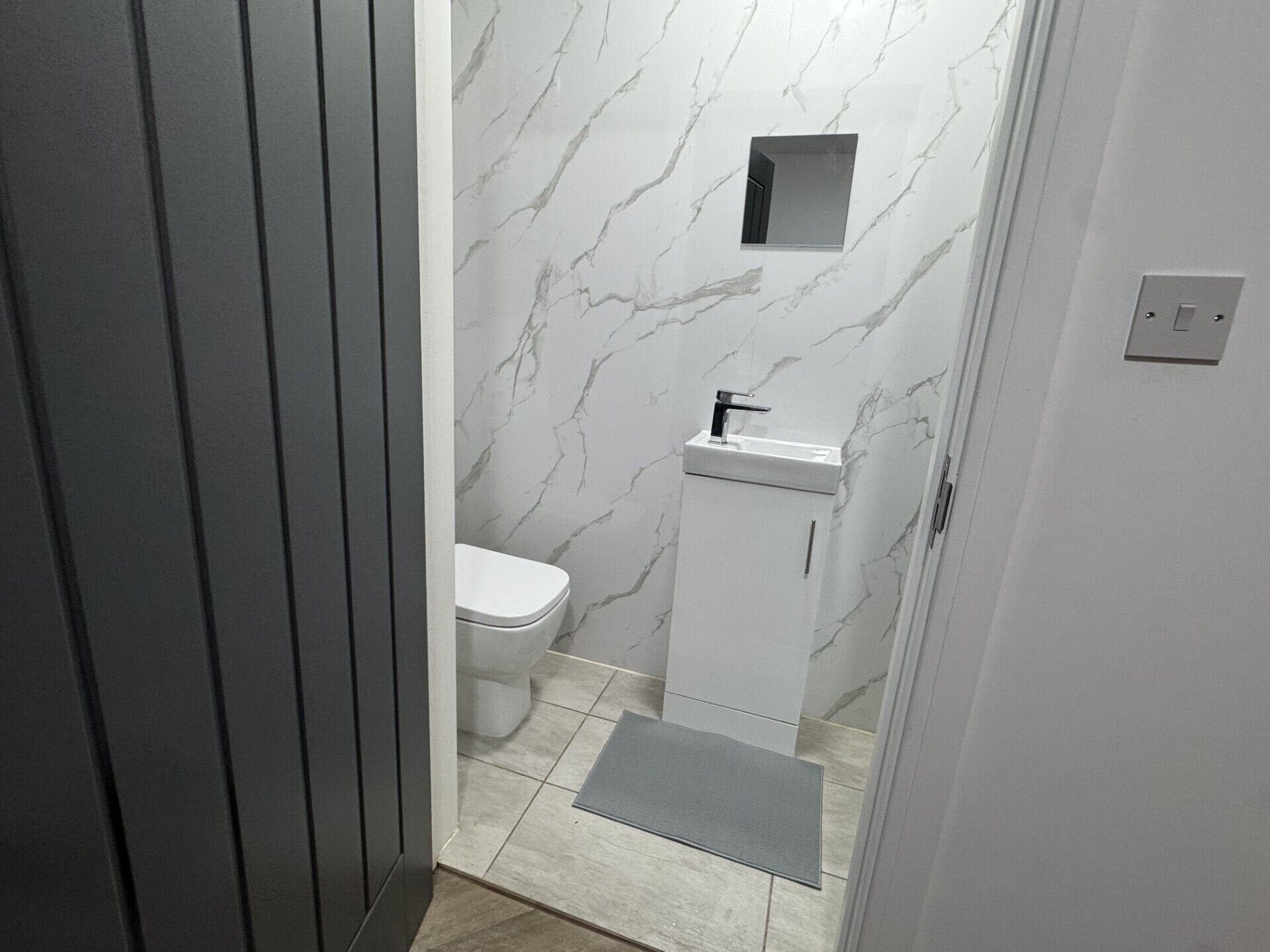 A modern bathroom with a toilet, sink, and marble walls.