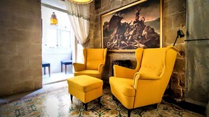 Una stanza con due poltrone gialle, un pavimento decorato, un quadro appeso al muro e una porta che conduce in un'altra stanza.