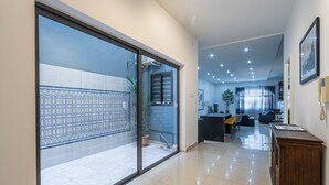 Een ruime hal met een schuifdeur van glas naar een balkon met betegelde vloer.
