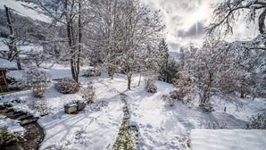 Schneebedeckte Landschaft mit einem Steinweg, Bäumen und einem kleinen Gebäude.