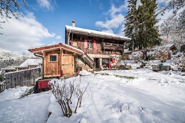 A wooden cabin with a balcony, a wooden door, and a snow-covered landscape.