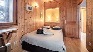 Ein Zimmer mit Holzwänden, einem Bett, einem Schreibtisch und einer Tür.