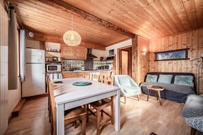 A wooden-paneled room with a dining table, chairs, a sofa, and a TV.