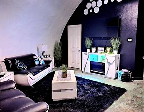 Ein Wohnzimmer mit schwarzem Sofa, weißem Couchtisch und Kamin.