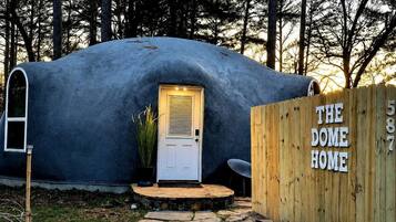 A dome-shaped structure with a door and a wooden fence labeled 'THE DOME HOME.'
