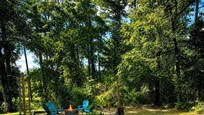 A backyard with a fire pit, two blue chairs, and a black grill. - Dome Home at Lake Palestine: Unique Dome Rental in Bullard, Texas (Bullard)