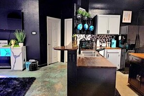 A modern kitchen with dark cabinetry, a central island, and a backsplash with blue accents.