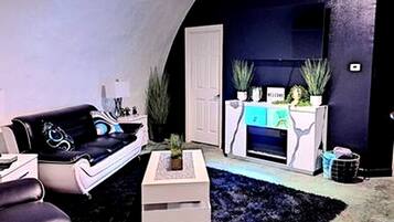 A living room with a black sofa, a white coffee table, and a fireplace.