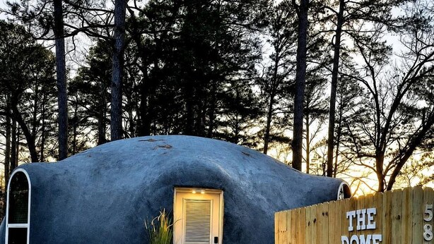 Una estructura abovedada con una puerta y una cerca de madera que dice 'THE DOME HOME'.