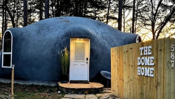 Una estructura abovedada con una puerta y una cerca de madera que dice 'THE DOME HOME'.