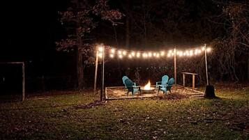 An outdoor seating area with chairs and a fire pit, surrounded by string lights.