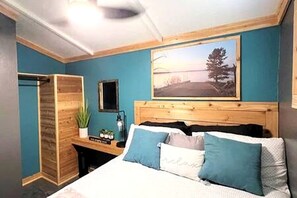 Ein Schlafzimmer mit Bett, Schreibtisch, Spiegel, einem Bild an der Wand und einem Kleiderschrank.